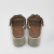 Klapki w kolorze brązowym widoczne z tyłu. Dwa paski zdobione rzędem trójwymiarowych kwiatów z kryształkami. Na ciemnych wkładkach znajduje się złote logo Maria Pakulnis. Widoczny gęsty splot platformy.